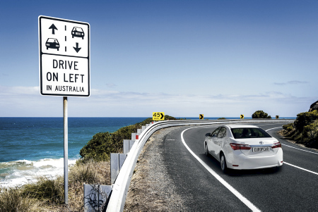 weisses Auto der Europcar Flotte auf Küstenstrasse vor Hinweisschild